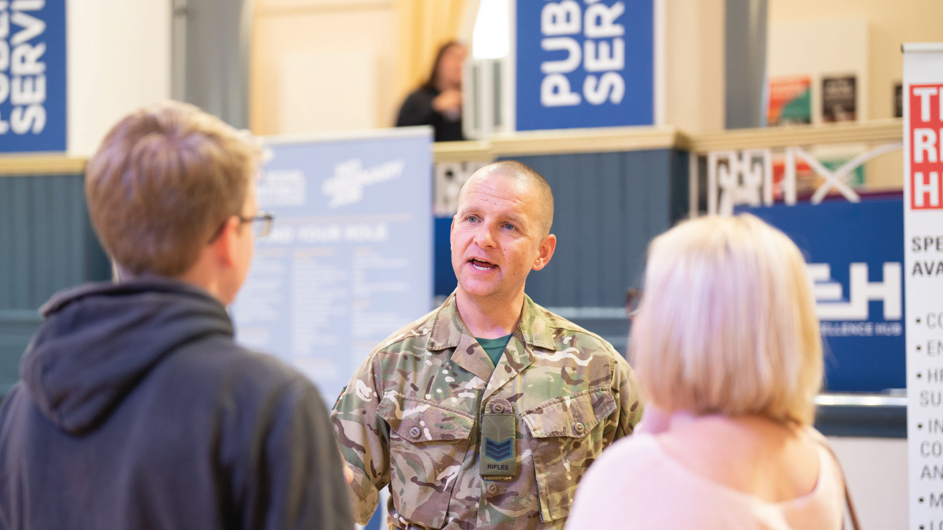 man from the army talks to parent and potential student at public services stand