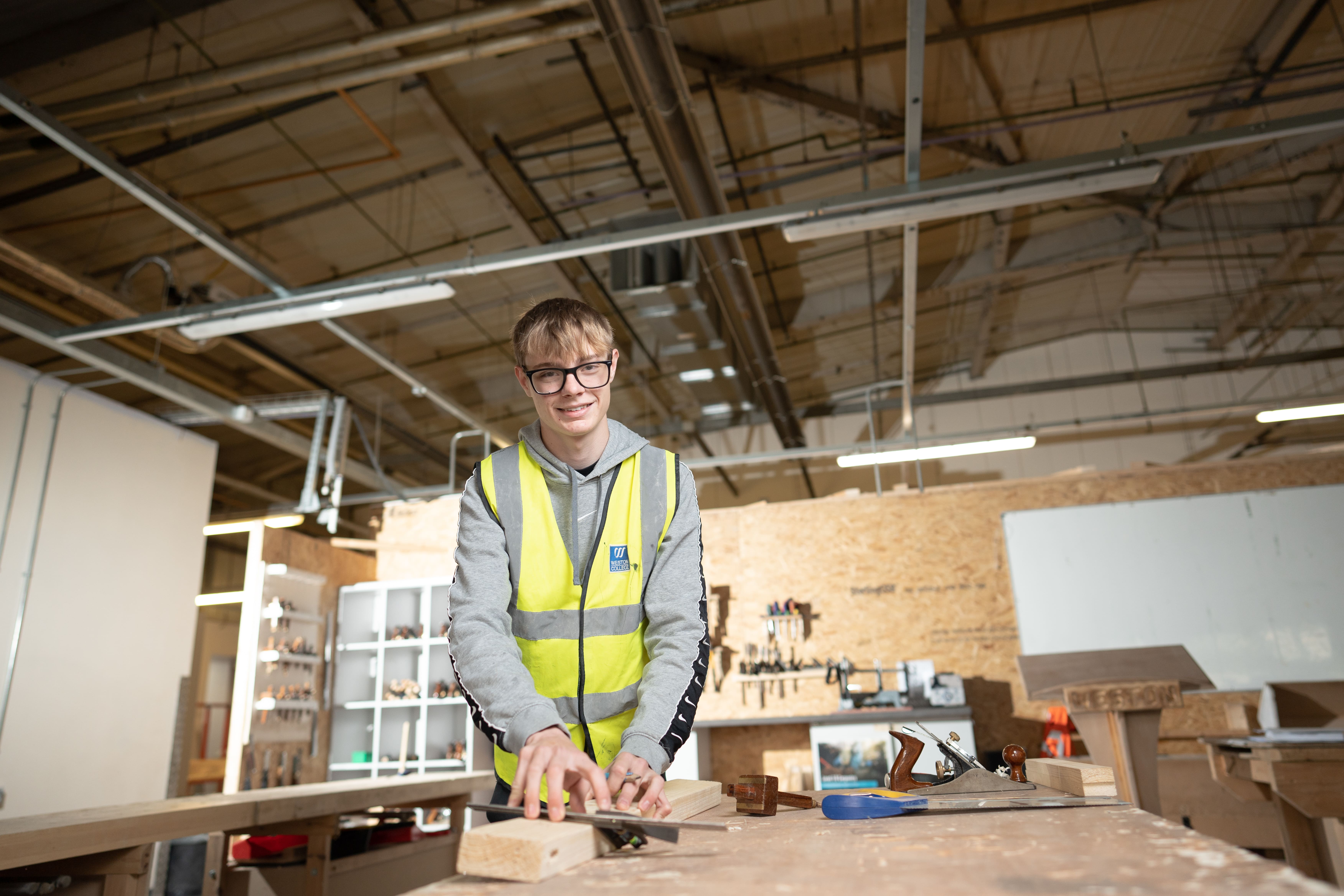 carpentry student smiling at the camera while practicing carpentry