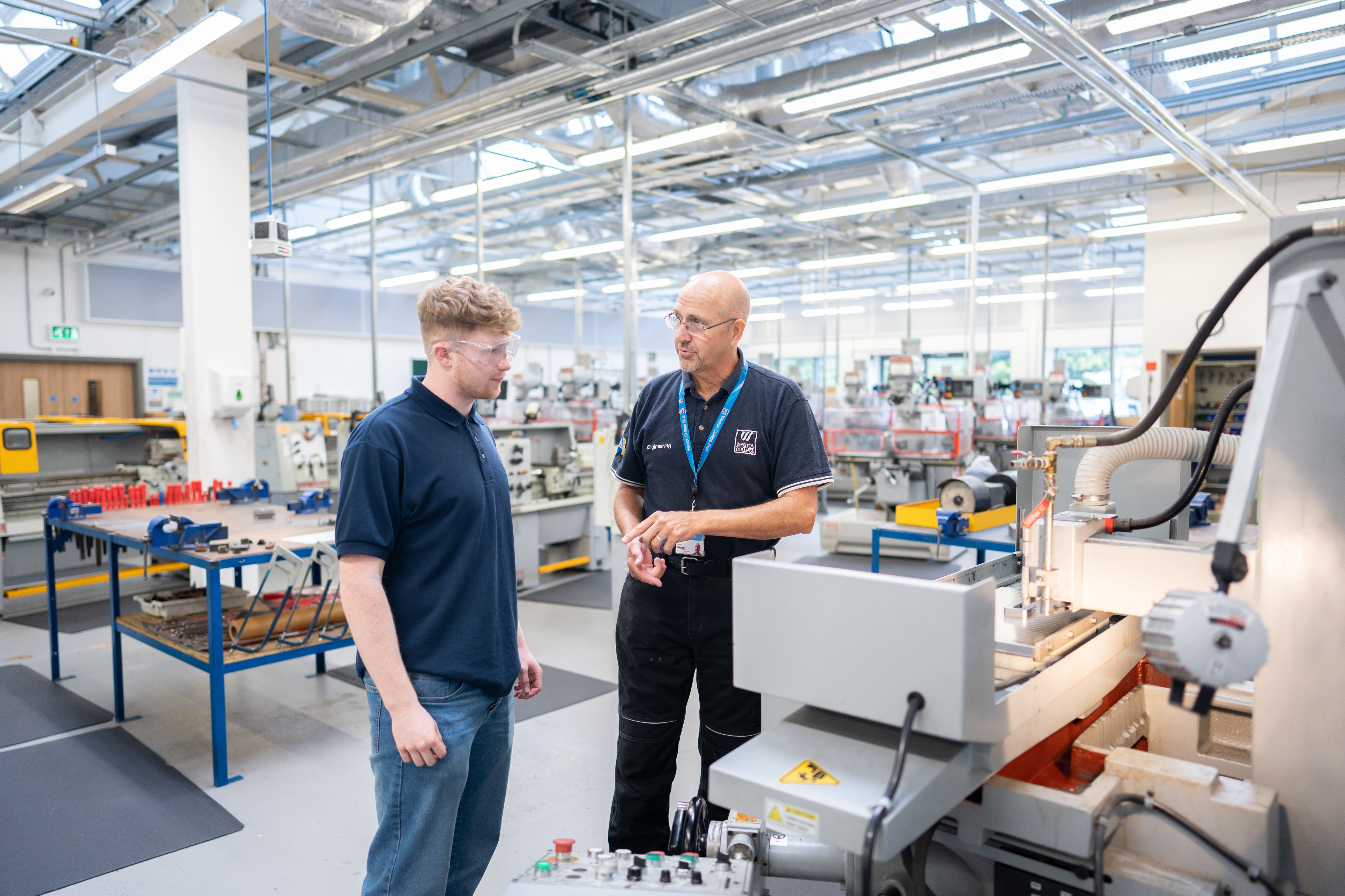 lecturer explaining something to a student in engineering machine warehouse  