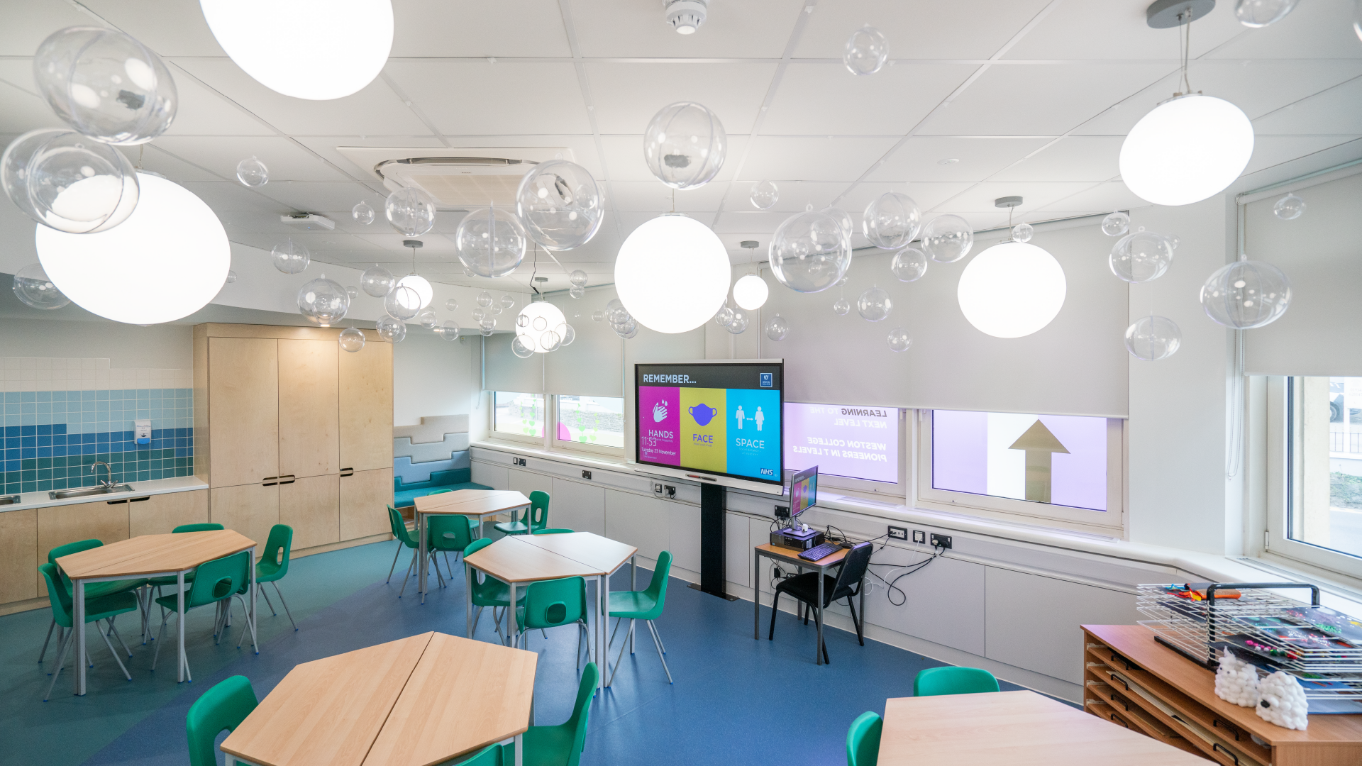 a early years classroom with tables and chairs and a computer