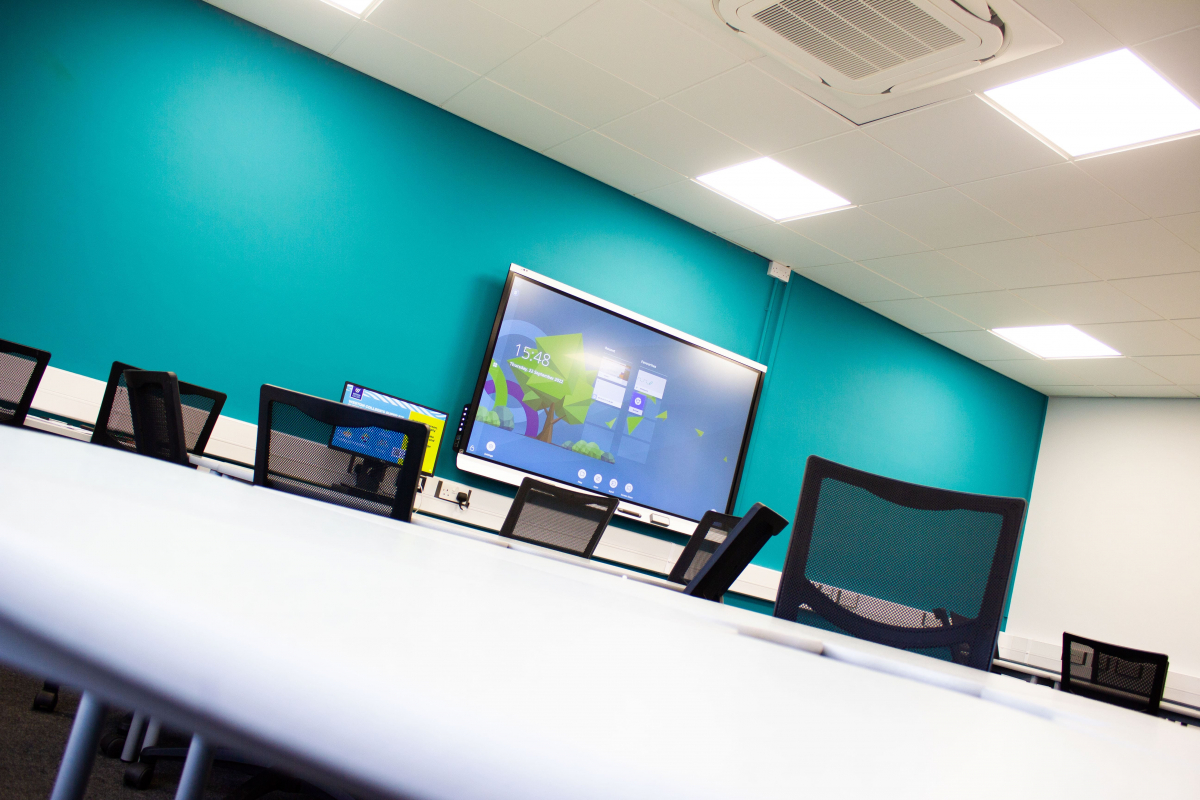 business classroom close up of circle tables with chairs around showing interactive whiteboard
