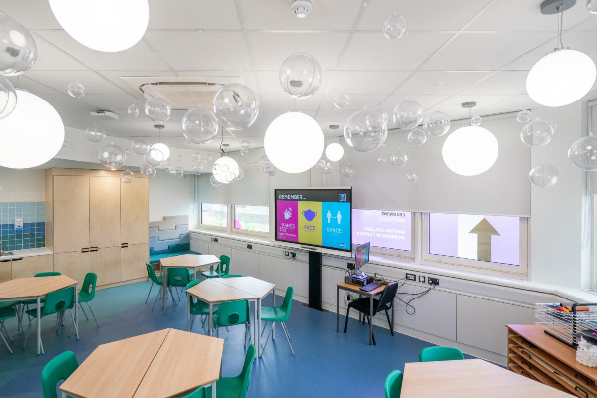 a early years classroom with tables and chairs and a computer