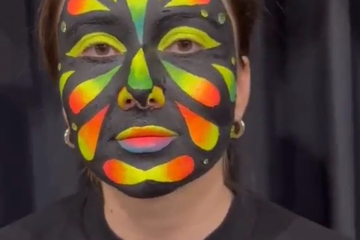 Student with her face painted in the neon yellow, orange and black like a butterfly