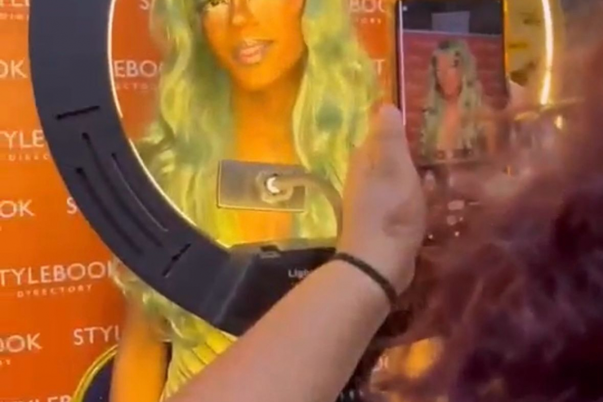 Student face painted orange with a long green wig