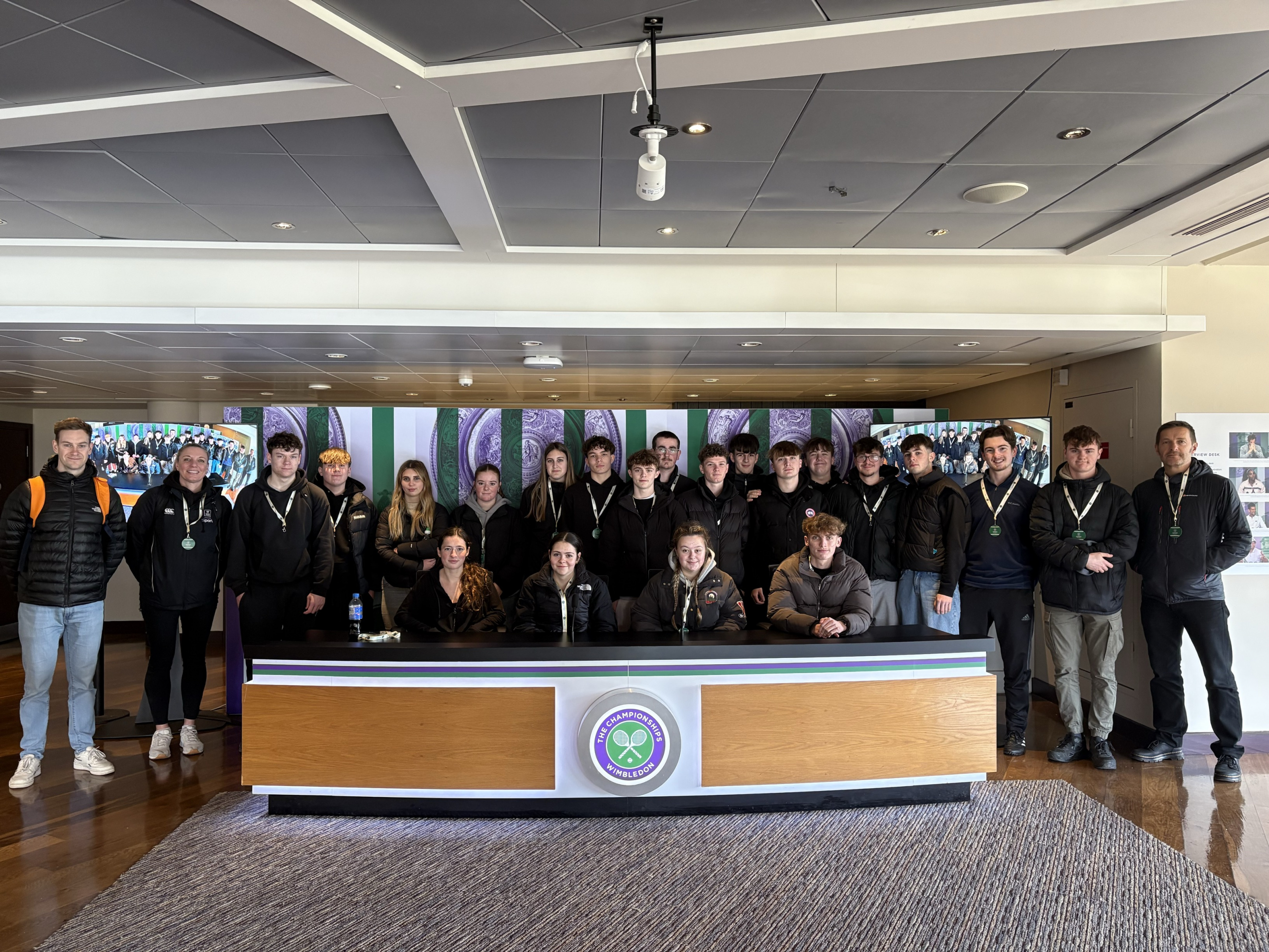 Sport students standing behind the Wimbledon spectator desk