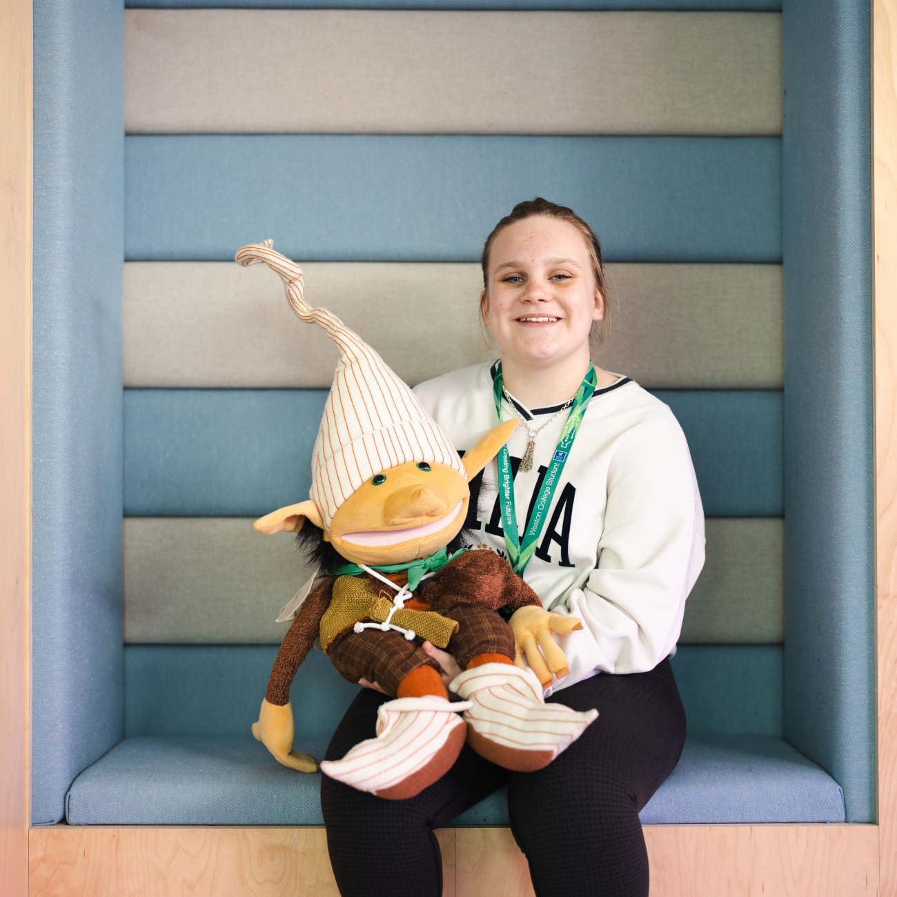 female early years student smiling while holding a puppet