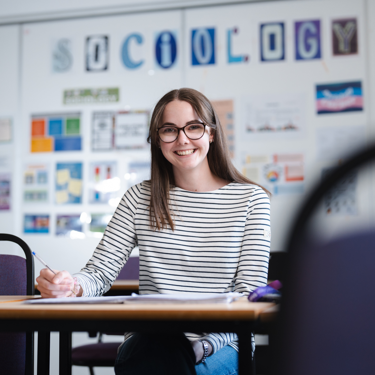 Student sat smiling whilst writing in a book