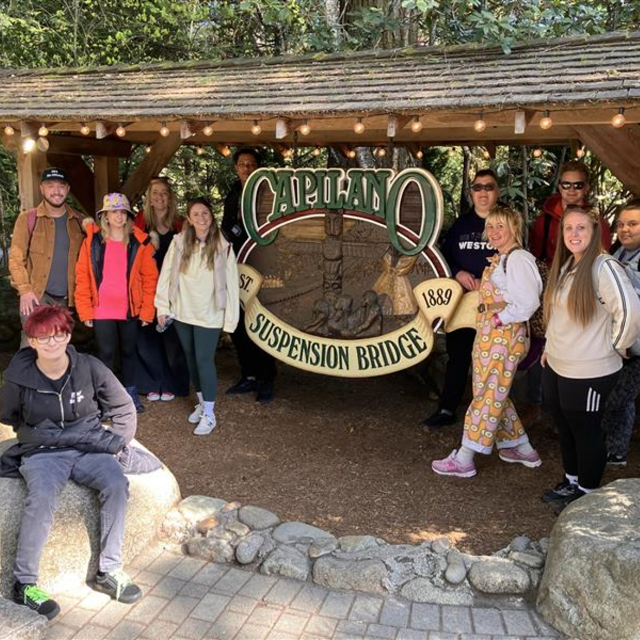 Students and staff standing next to the Capilano Suspension Bridge sign