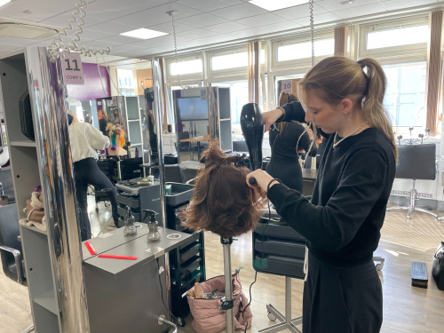 Student giving the hair mannequin a blow out