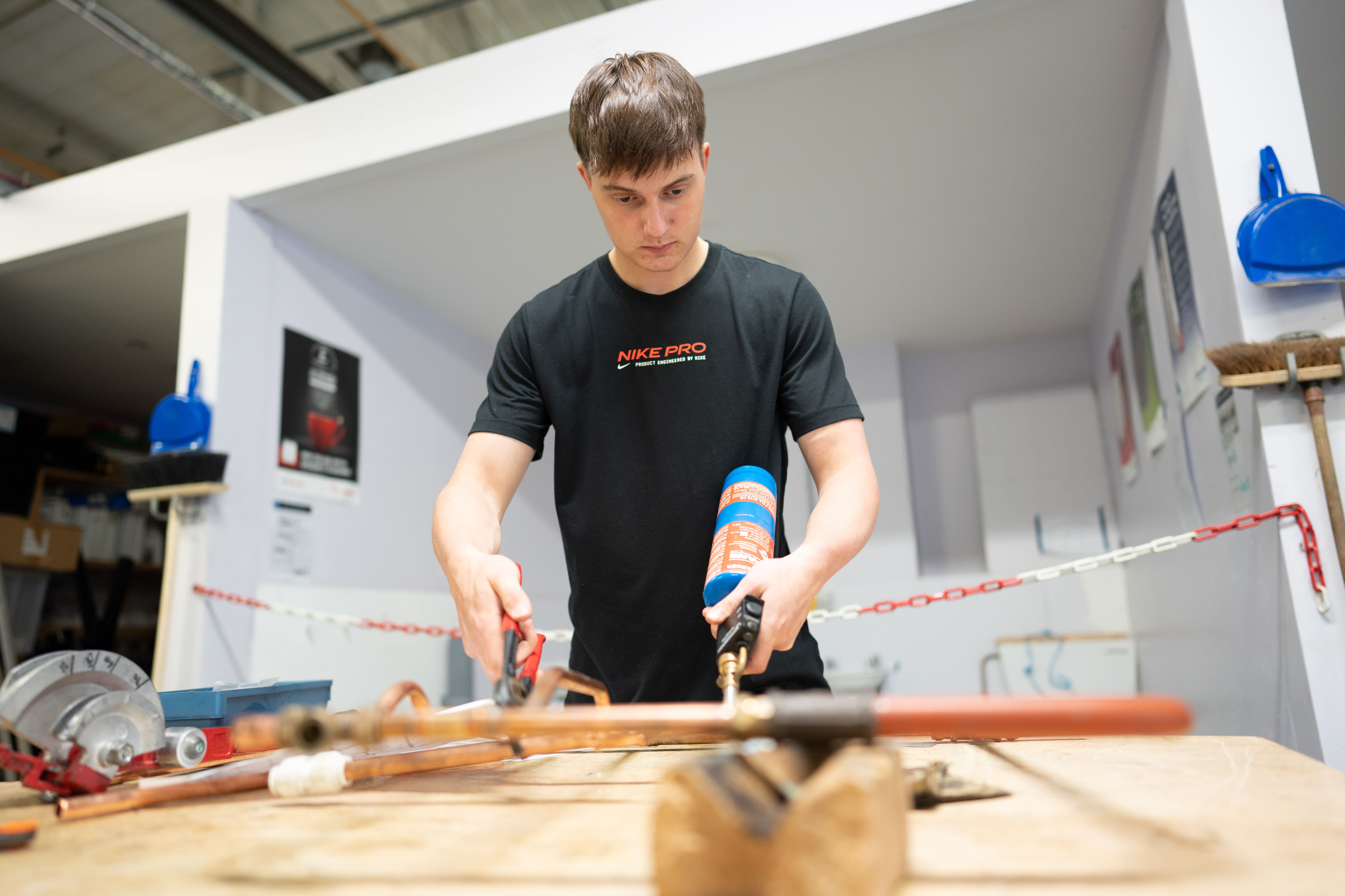 Student using a blow touch on copper pipes